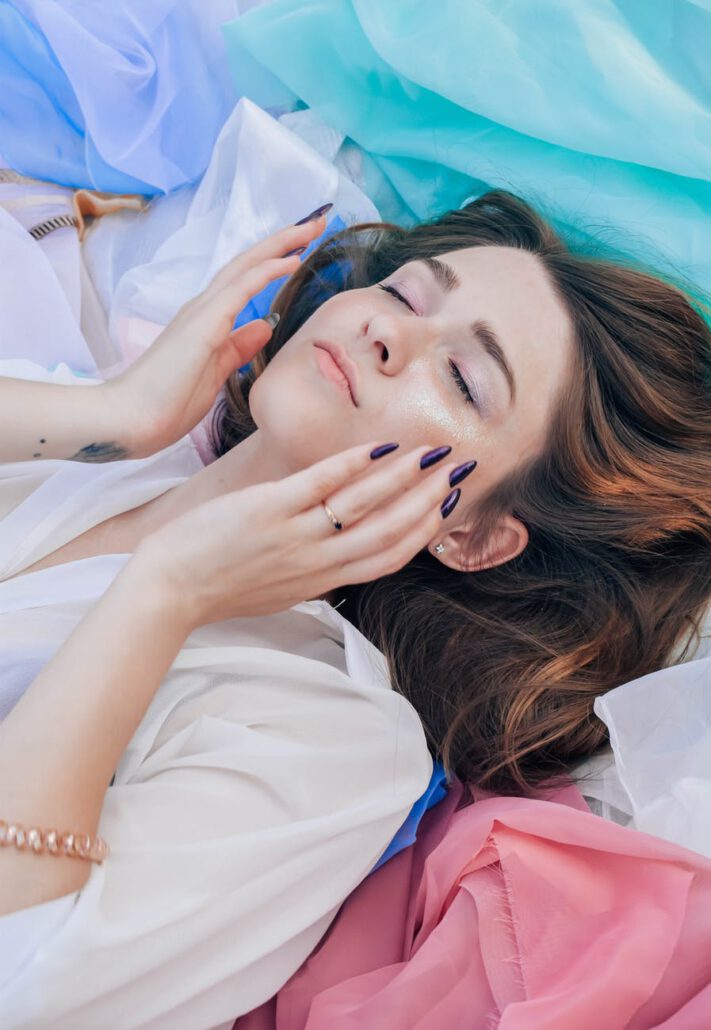 woman in white top lying on assorted color textiles