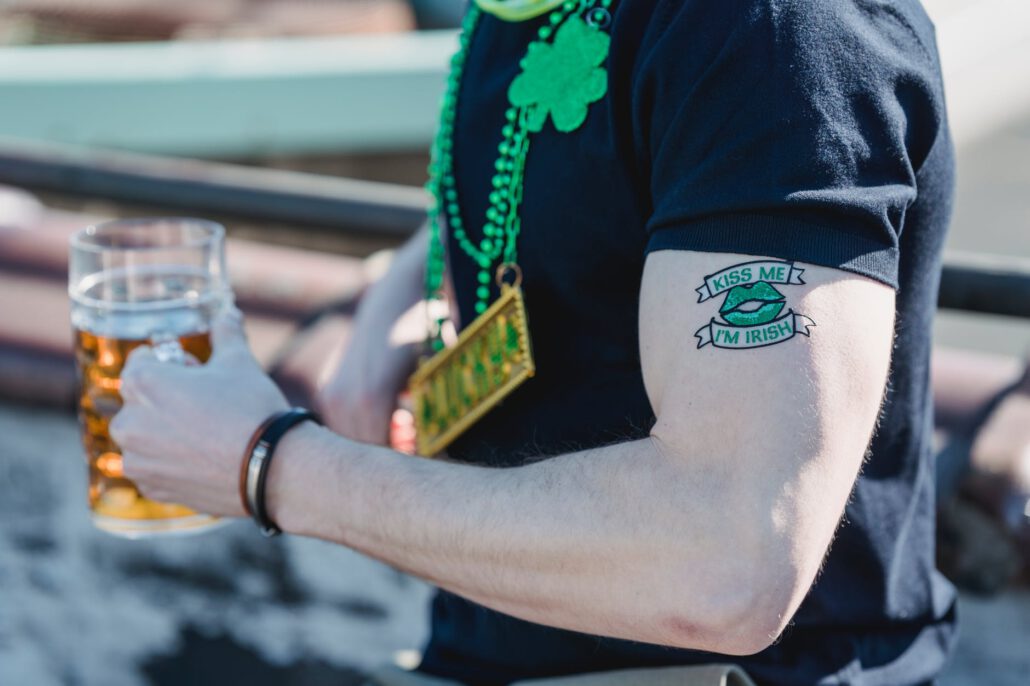 unrecognizable guy with creative tattoo drinking beer on st patricks day